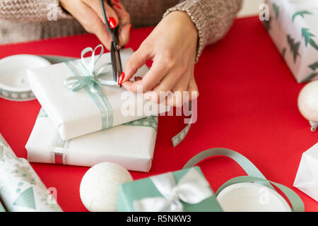 DIY Geschenkverpackung. Nicht erkennbare Frau Verpackung schöne Weihnachtsgeschenke im nordischen Stil. Die Hände schließen. Stockfoto