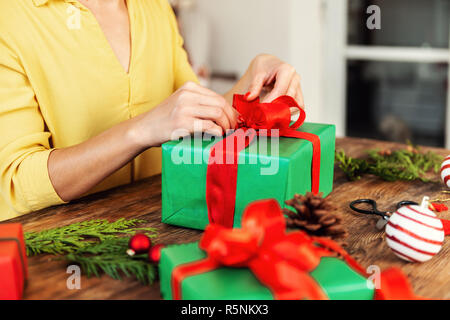 DIY Geschenkverpackung. Nicht erkennbare Frau Verpackung schöne Rote und Grüne Weihnachten Geschenke. Stockfoto