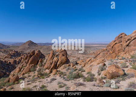 Eine Wüste mit Felsformationen, Täler und der entfernten Bergkette am Horizont. Ein Blick von der Spur der Joshua Tree National Park, Kalifornien, USA. Stockfoto