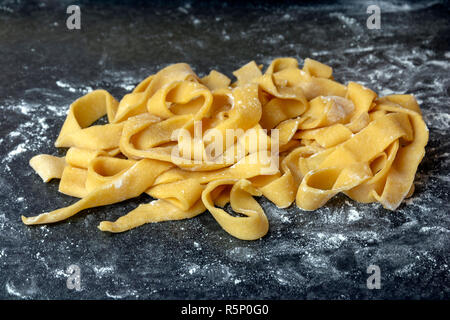 Home gemacht dicke Tagliatelle schließen bis auf eine schwarze Fläche mit einer geringen Tiefenschärfe abgewischt. Stockfoto