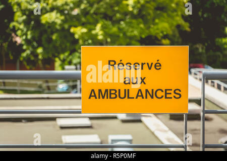 Gelbes Schild oder es ist in Französisch geschrieben: Reserviert für Krankenwagen Stockfoto