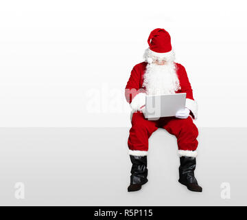 Santa Claus, Laptop und sitzen auf Leeres Bedienfeld Stockfoto