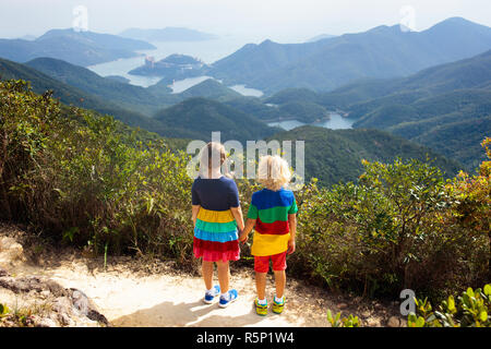 Familie mit Kindern wandern in Hong Kong Berge. Schöne Landschaft mit Hügeln, das Meer und die Stadt Wolkenkratzer in Hong Kong, China. Aktivität im Freien in der Stockfoto