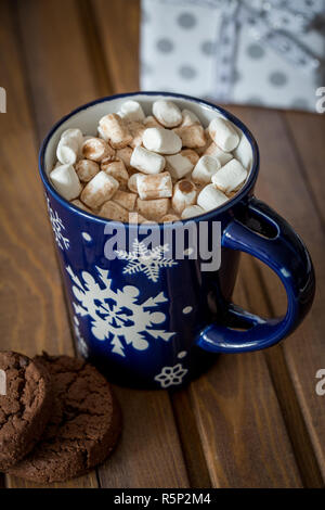 Süße leckere heiße Schokolade mit Marshmallows in blauer Schale mit Keksen, vorhanden in der Nähe von Holz Hintergrund. Weihnachten Komposition. Stockfoto