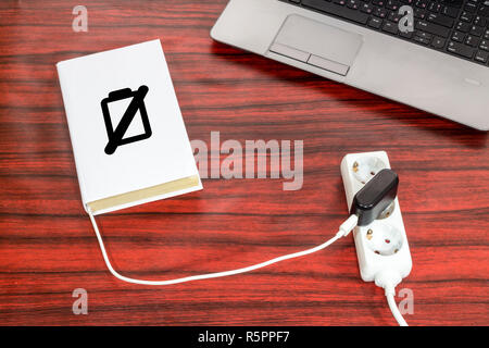 Buch an eine Steckerleiste über ein USB-Ladegerät angeschlossen ist. Das Batteriesymbol zeigt den Ladezustand. Stockfoto