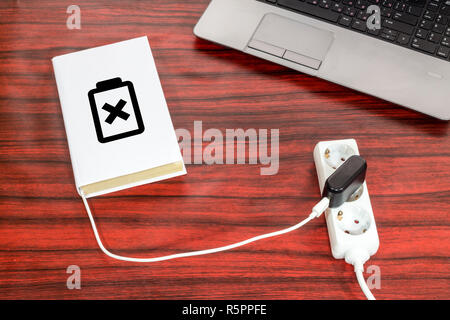 Buch an eine Steckerleiste über ein USB-Ladegerät angeschlossen ist. Das Batteriesymbol zeigt den Ladezustand. Stockfoto