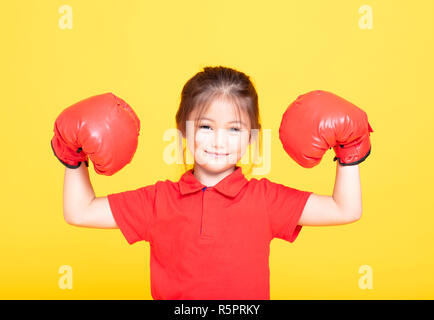 Glückliche kleine Mädchen mit roten Boxhandschuhen auf gelbem Hintergrund Stockfoto