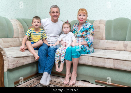 Portrait der Großmütter und Großväter mit Enkeln sitzen auf der Couch Stockfoto
