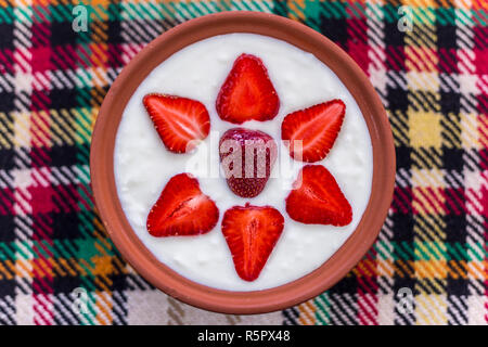 Erdbeeren in Scheiben geschnitten und schön in eine Schale mit Joghurt angeordnet. Stockfoto