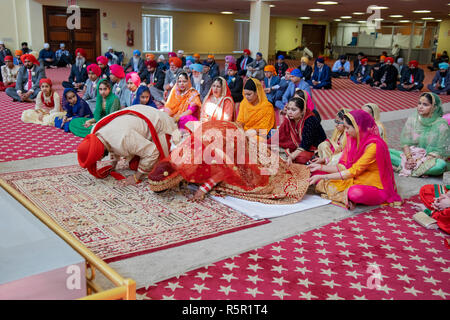 Ein Sikh Braut und Bräutigam Verbeugung während ihrer Hochzeit Zeremonie an einem Tempel in Richmond Hill, Queens, New York Stockfoto