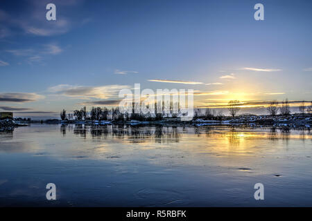 Die IJssel in der Nähe von Zutphen, Niederlande unter einem fast wolkenlosen blauen Himmel im Winter im ruhigen Wasser widerspiegeln Stockfoto