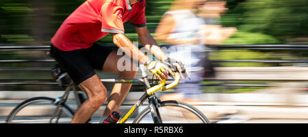 Mann Ausübung schnell auf seinem Rennrad im Central Park in New York City mit der Hintergrund verschwommen. Stockfoto