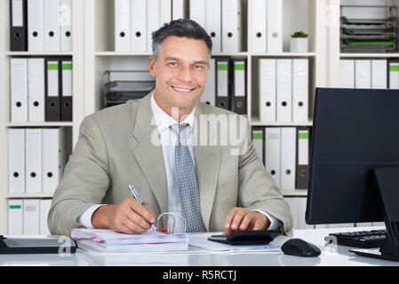 Zuversichtlich Buchhalter mit Rechner beim Schreiben von Dokumenten Stockfoto