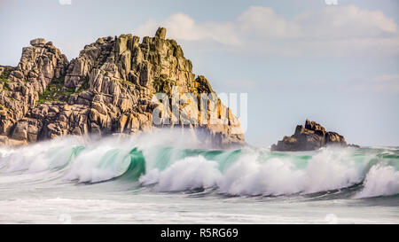 Dies ist der Felsvorsprung im Porthcurno Beach, Cornwall mit einem großen grünen/blauen Welle ins Rollen mit "weisse Pferde" auf der Startseite. Es war ein schöner Tag Stockfoto