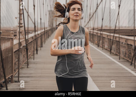 Praktizierende Frau Joggen auf der Brooklyn Bridge Stockfoto