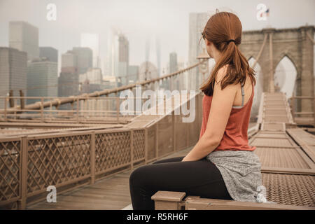 Frau sitzt auf der Brooklyn Bridge und suchen die Ansicht Stockfoto