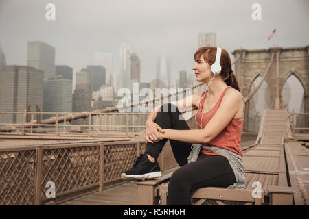 Frau sitzt auf der Brooklyn Bridge und suchen die Ansicht Stockfoto