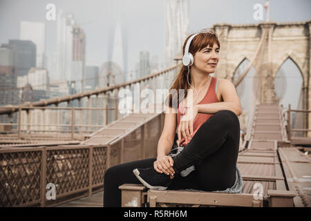 Frau sitzt auf der Brooklyn Bridge und suchen die Ansicht Stockfoto