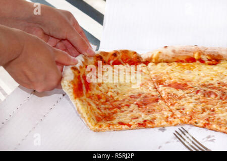 Hände, die Scheiben Pizza Margarita. Hand auf ein Stück leckere Pizza, aus der Nähe. Italienische traditionelle klassische Pizza in der Box gehalten wird. Stockfoto