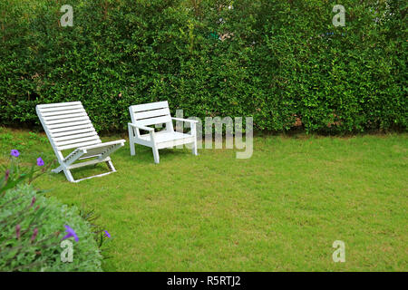 Zwei unterschiedliche Art der weißen Holzstühlen in leuchtenden grünen Garten farbige Stockfoto