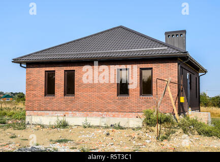 Das Haus mit Kunststoff Fenstern und einem Dach aus Wellblech. Braun Braun Dach und Ziegel Stockfoto