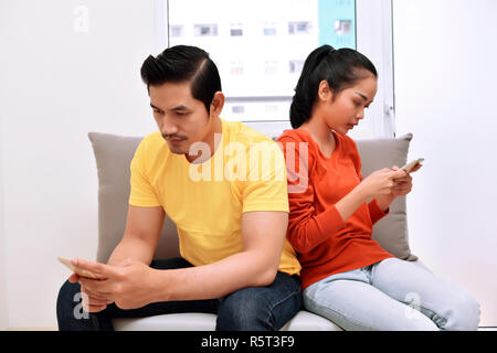 Portrait von asiatischen Paar beschäftigt mit ihren Handys in Ihrer Hand Stockfoto