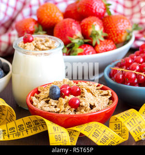 Gläser mit frischem Joghurt, Beeren, Müsli und Maßband Stockfoto