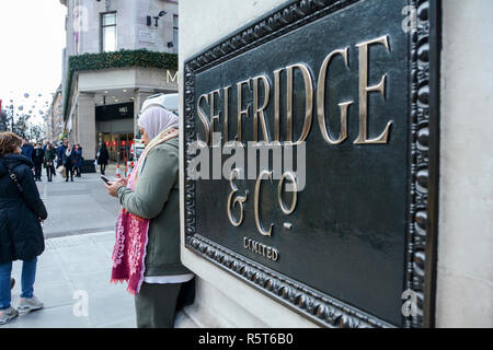 Eine Frau sms außerhalb Selfridges der berühmten Londoner Kaufhaus, in der Oxford Street, London, UK Stockfoto