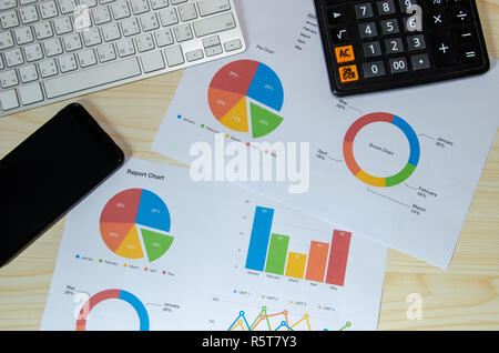 Geschäftliche Dokumente finanzielle Grafiken Analyse und Tastatur mit Smart Phone auf dem Schreibtisch. Stockfoto