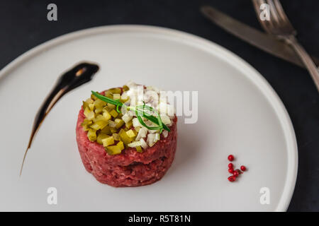 Beef Tartare mit Gurken und frische Zwiebel an der Platte. Stockfoto
