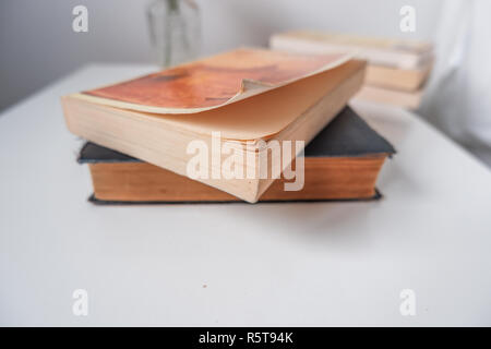 Ein alter Hund eared Taschenbuch Buch auf einem Tisch in einem weißen Innenraum Stockfoto