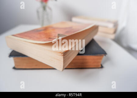 Ein alter Hund eared Taschenbuch Buch auf einem Tisch in einem weißen Innenraum Stockfoto