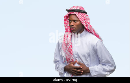 Junge arabische afrikanischen Mann mit traditionellen Kufiya über isolierte Hintergrund mit Hand auf Magen, Verdauungsstörungen, schmerzhafte Krankheit Gefühl unwel Stockfoto