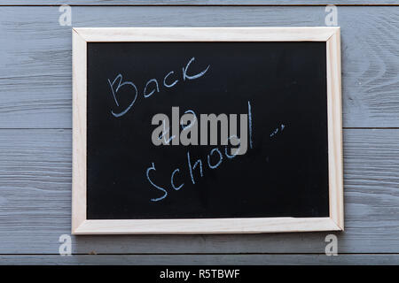 Schwarzes Brett mit zurück in die Schule Inschrift auf schiefertafel und Kreide auf grau Holz- Hintergrund geschrieben, angefangen neue Schuljahr Konzept, elementare ed Stockfoto