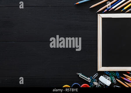 Zurück zu Hintergrund Schule mit Schreibwaren Bürobedarf für moderne elementare Bildung, Buntstifte, Farben und Rahmen auf dunkel schwarz Holz- Schüler Schreibtisch, w Stockfoto