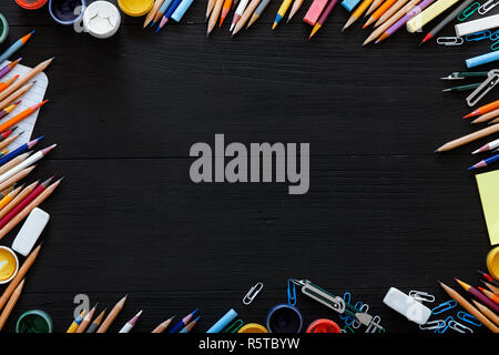 Verschiedene Schreibwaren Bürobedarf auf dunklen Tisch, kreativen pädagogischen Hintergrund für Website mit Buntstifte, Farben auf Schwarz Holz- Schreibtisch, zurück zur Scho Stockfoto