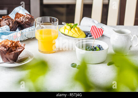 Frühstück am Valentinstag serviert mit Muffins, Saft, Beeren und Obst auf weißer Tisch. Stockfoto