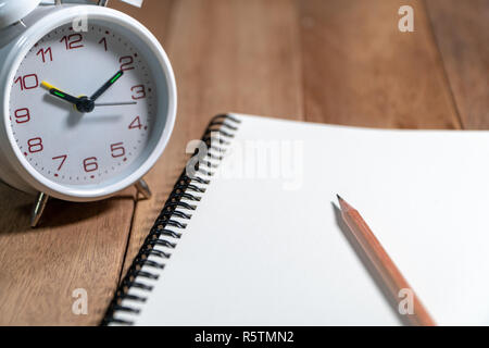 Holz- Bleistift auf der leeren Notebook mit weißen vintage Wecker auf dem hölzernen Tisch platziert. Kopieren Sie Platz für Text hinzufügen. Stockfoto