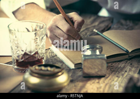 Schriftsteller bei der Arbeit. Die Hände der jungen Schriftsteller sitzen am Tisch und etwas Schreiben in seinem Skizzenbuch Stockfoto