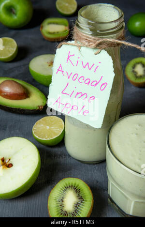 Frisches rohes Obst und einen gemischten Grünen Smoothie in einer Flasche, auf einem Küchentisch. Gesundes Frühstück mit grünem Essen und Trinken Stockfoto