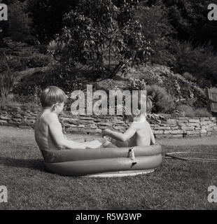 1960, historische, draußen im Garten, zwei kleine Jungen sitzen in einem kleinen Gummi Planschbecken. Stockfoto