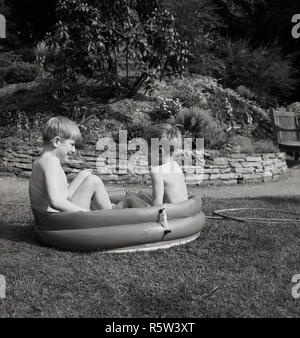 1960, historische, draußen im Garten, zwei kleine Jungen sitzen in einem kleinen Gummi Planschbecken. Stockfoto