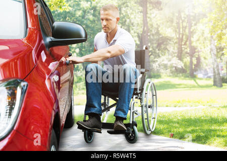 Mann auf Rollstuhl Öffnen der Fahrzeugtür Stockfoto