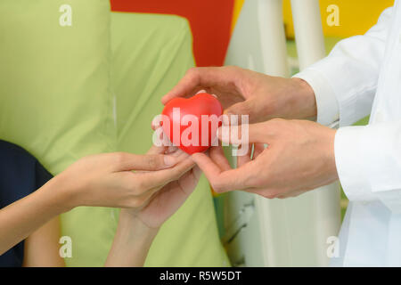Arzt Hand, rotes Herz an Patienten Frau Stockfoto