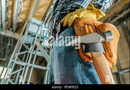 Kaukasische Auftragnehmer Werkzeuge Riemen Nahaufnahme mit einem Hammer. Bauindustrie Thema Stockfoto