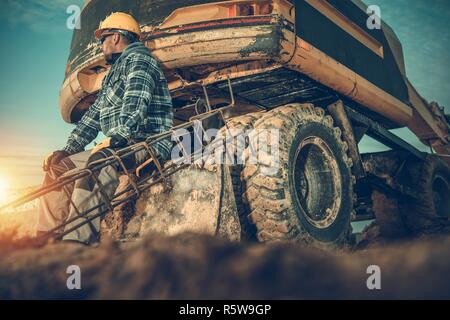 Kaukasische Baustelle Bagger Arbeiter tragen gelbe harten Hut. Bagger und eine Stahlarmierung Elemente. Stockfoto