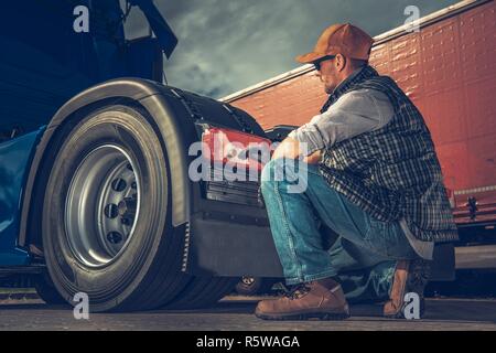 Kaukasische LKW-Fahrer in seinem 30s Prüfen Beleuchtung hinten in seinem Halb Lkw Traktor. Stockfoto