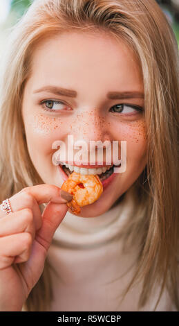 Junge schöne Frau essen schwarze Nudeln mit Meeresfrüchten und Tintenfisch Tinte in das Restaurant im Freien. Lustig und schön. Stockfoto