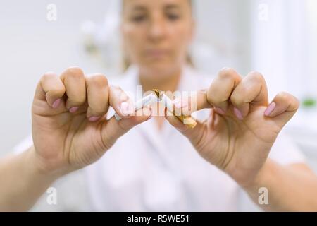 Arzt Zahnarzt bricht eine Zigarette, Zigarette, Hintergrund Zahnarztpraxis. Rauchen aufhören. Stockfoto