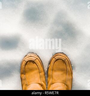 Die Beine der Frauen in Stiefeln im Schnee, Winter kommt, Hallo Winter, kopieren Raum oben, Ansicht von oben. Stockfoto